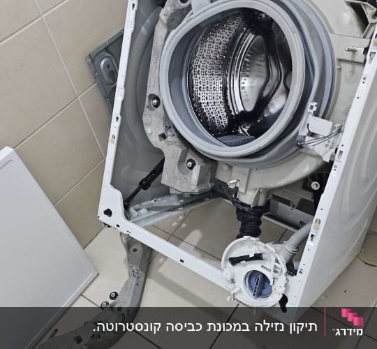 מכונת כביסה פתוחה עם כלים לתיקון על הרצפה